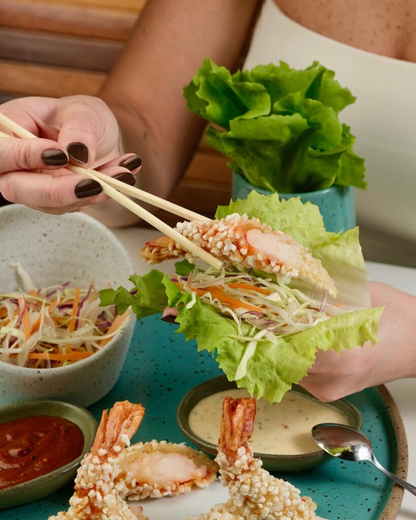 O Hand Salad com tempurá de camarão em tapioca e folhas crocantes Gurumê reinterpreta um dos grandes sucessos da casa em versão ainda mais leve e contemporânea. Não se trata de um preparo clássico da cozinha japonesa, mas de uma criação exclusiva do Gurumê: um hand roll reinventado, que substitui a alga nori por uma lâmina de tapioca delicadamente tostada e combina texturas de folhas crocantes com o tempurá de camarão, resultando em uma experiência fresca, elegante e feita para ser apreciada com as mãos.